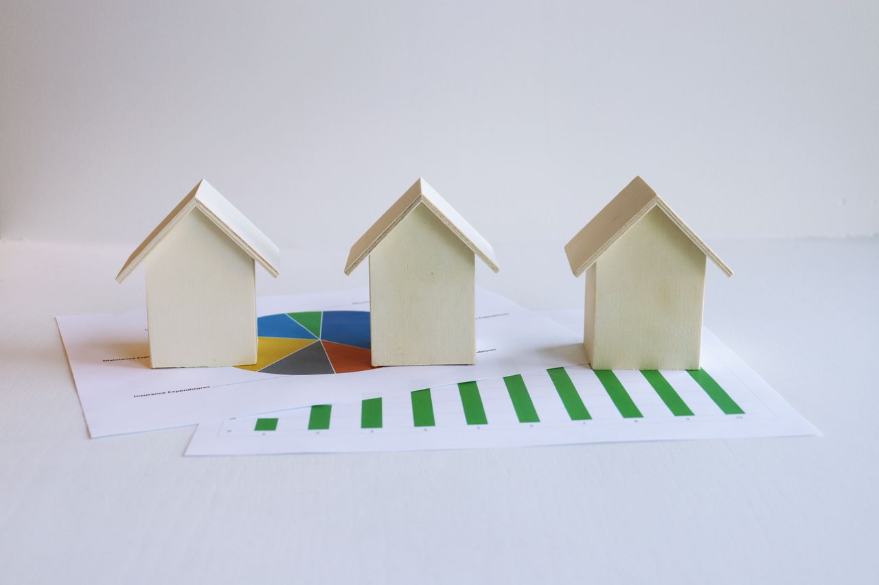 Crafting Captivating Headlines: Your awesome post title goes here Wooden model houses on graphs depict real estate market analysis and trends.