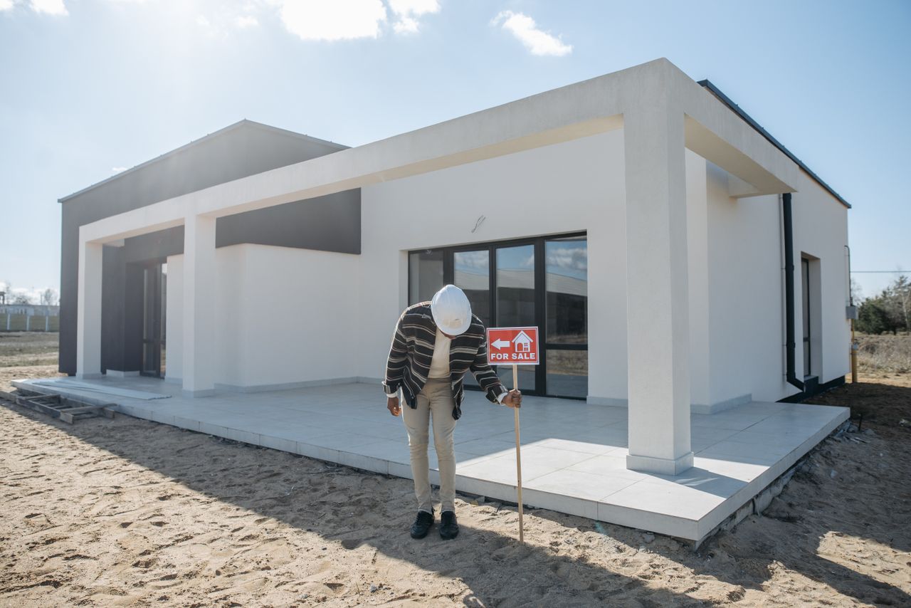 The Art of Drawing Readers In: Your attractive post title goes here Real estate agent with hard hat standing by a modern house for sale.
